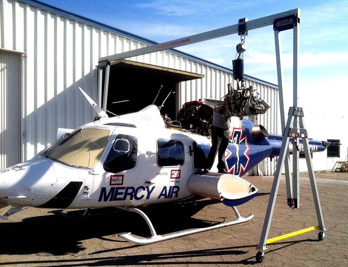 Grúa pórtico de aluminio eme con una viga dividida posicionada sobre un helicóptero para el izaje de un componente