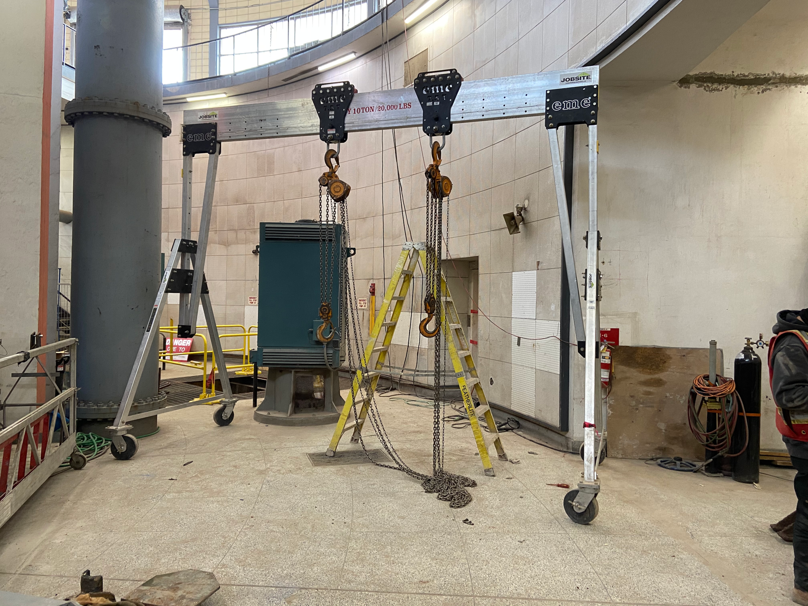A 10 ton portable aluminum crane being used for a subterranean lift with two chain hoists